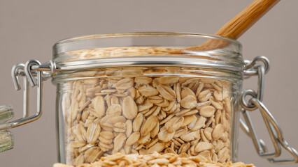 Close-up of rolled oats stored in a glass jar with a wooden spoon, representing sustainable and...
