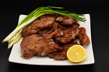 Fresh fried pork kebab with lemon and onion on a white plate. Barbecue meat.