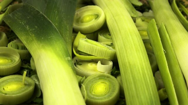 Whole and cut, peeled and unpeeled leek and celery lie on a chopped dill and parsley