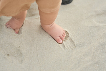 there is a baby standing on the sand with his feet in the sand