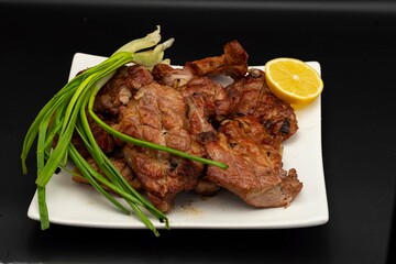Fresh fried pork kebab with lemon and onion on a white plate. Barbecue meat.