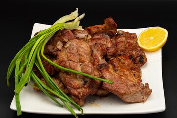 Fresh fried pork kebab with lemon and onion on a white plate. Barbecue meat.