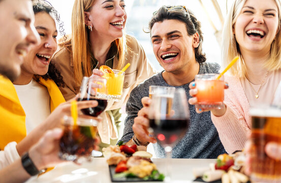 Multiracial friends celebrating party drinking cocktails at bar restaurant - Young people having fun hanging out on weekend day - Life style concept with guys and girls enjoying time together