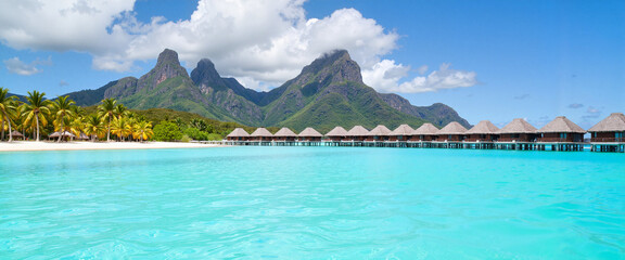 Tranquil lagoon with overwater bungalows under sunny skies, paradise