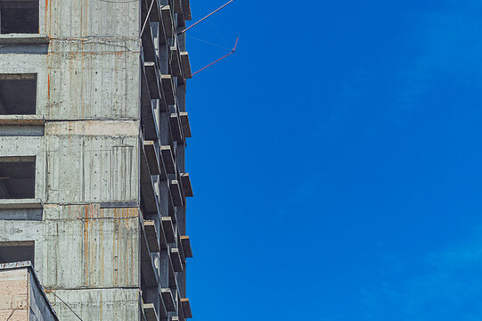 Walls of high-rise monolithic building under construction with window openings and floor ceilings on clear blue sky background and copy space. Rust drips of reinforced concrete structures flowed down