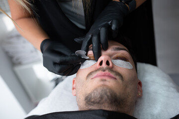 Fototapeta premium A young guy in a beauty salon, the concept of eyelash care