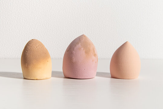 Three cosmetic sponges on white background. New sponge, slightly dirty and old sponge