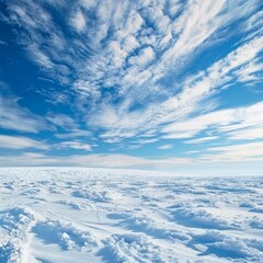 Naklejka premium Snow covered field stretching under a vast blue sky dotted with wispy cirrus clouds, creating a serene winter scene