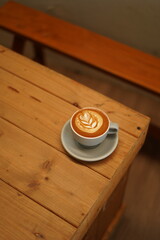a cup of latte art on the wood table
