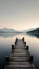 A wooden pier stretches into a serene lake, mountains rise in the distance under a calm sky