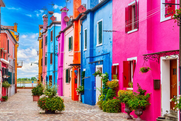 Beautiful vibrant colorful houses with green plants in pots on Burano island near Venice in Italy.