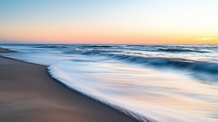 Obraz premium Sunrise ocean waves gently lapping sandy beach. Coastal serenity.
