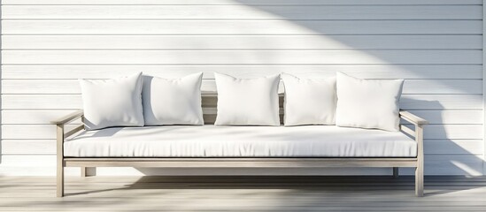 Modern outdoor sofa with white cushions against a light wooden wall featuring copy space for text placement.