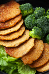 Golden-brown pancakes served with steamed broccoli and fresh lettuce. A healthy and delicious meal.