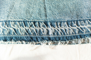 Close-up of distressed denim fabric.  The frayed edges and textured weave showcase the garment's...
