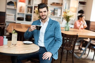 Handsome young man enjoying coffee at cafeteria.
