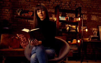 young 30s woman reading a book at home relaxing.