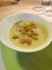Creamy soup with croutons in white bowl on green napkin at dining table