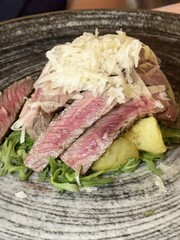 Succulent steak salad with parmesan and arugula on rustic plate