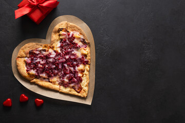 Food for Valentine's Day. Heart shaped sweet pizza with pineapple on black background. View from above. Copy space. Romantic dinner.