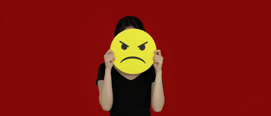 Woman holding yellow angry face emoji, red background