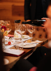Pouring sparkling wine into a glass at a festive dinner table with elegant decorations