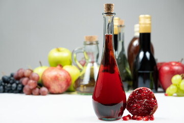 Pomegranate vinegar against the background of fruits and other types of vinegars