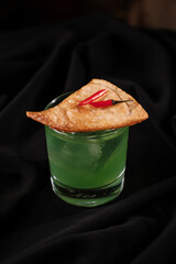 Green cocktail topped with nachos and hot peppers