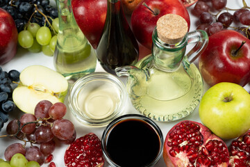 Different types of vinegar apple, balsamic, wine and pomegranate in vinegar bowls among fruits.