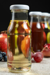 Fruit vinegars in glass bottles among fruits.