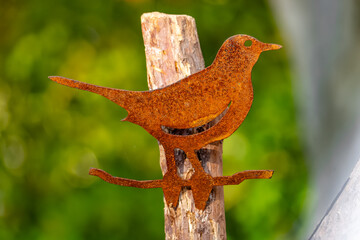 A bird sculpture is sitting on a wooden post