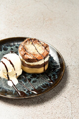 Indulge in a decadent layered dessert featuring rich chocolate, creamy filling, a scoop of vanilla ice cream, and artistic chocolate drizzle, all served on an elegant plate