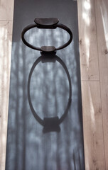 A pilates resistance ring on a yoga mat on a wood floor with interesting shadows