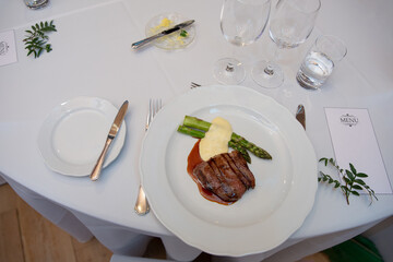 beef steak with asparagus on a white plate in a restaurant