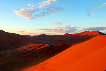 Naklejka premium Red sand dunes at sunrise in Sossusvlei in the Namib Desert, Namibia 