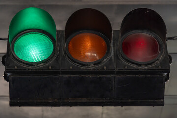 Horizontal vintage traffic light close-up. Metallic old-fashioned stoplight. Safety equipment is road signal of start traffic. Regulation safety with green, yellow, red lens. Warn retro style control.