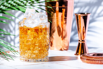Scotch and soda alcoholic cocktail drink with scotch whiskey, chilled soda and ice. White marble table, palm leaves and shadows