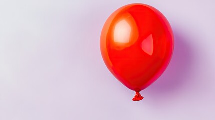single water balloon in vibrant red color placed on pastel lavender background with faint shadows