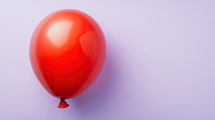 single water balloon in vibrant red color placed on pastel lavender background with faint shadows