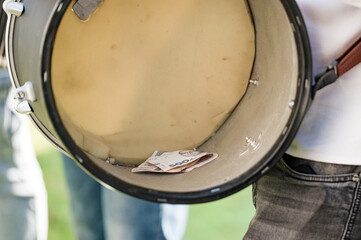 Close-up of a drum's interior showing folded banknotes.  The drum is being held by a person,...