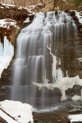 A long exposure blurred motion gorgeous cascading waterfall in the late winter, early spring, with melting snow and ice.