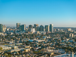 Fototapeta premium A drone photo taken high above Oakland, California, captures downtown during dusk. With a blue sky, buildings, architecture and city life