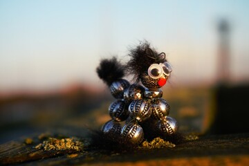 Creative hobby object made of beads that resembles an animal. A dog or cat as a pet that is looking for an owner with a red nose and big eyes.