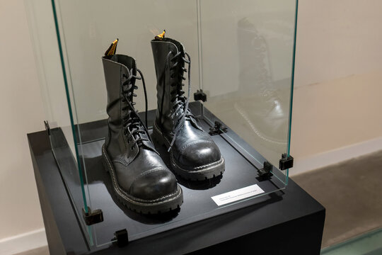 Black combat boots in museum display case, rock metal subculture symbol, vintage military footwear cultural concept, closeup on iconic 80s 90s fashion, alternative style