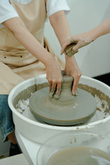 Potter's hands shaping clay on a wheel