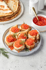 Pancake day, maslenitsa. Crepes, pancakes rolled with red caviar on white plate, gray background with text space