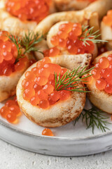 Pancake day, maslenitsa. Crepes, pancakes rolled with red caviar on white plate, close up