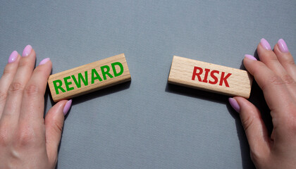 Risk or Reward symbol. Concept word Risk or Reward on wooden blocks. Businessman hand. Beautiful grey background. Business and Risk or Reward concept. Copy space