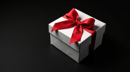 Obraz premium A pristine white gift box adorned with a vibrant red ribbon, a symbol of celebration and thoughtful gifting, rests elegantly on a stark black background