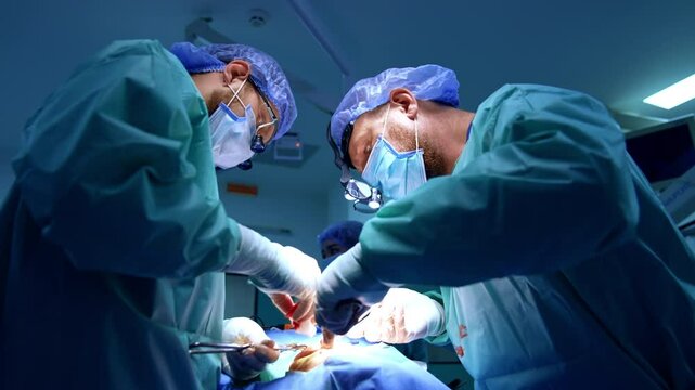 Caucasian bearded doctors carry out maxillofacial operation. Female scrub nurse stands at backdrop. Low angle view.